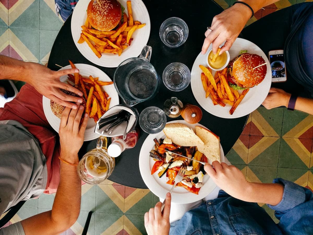 Friends sharing burgers and fries around a table, seen from above